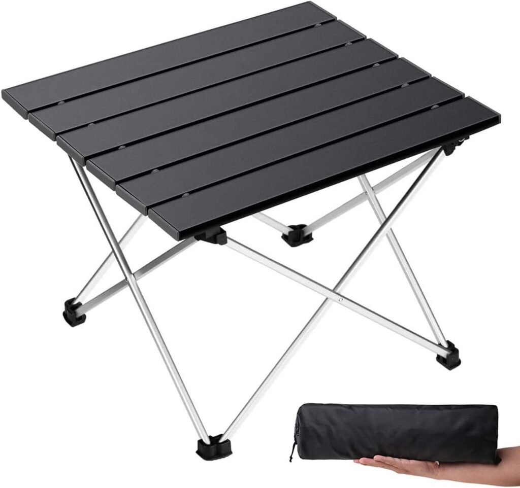 Foldable wine table holding wine, snacks, and glasses in a grassy area.