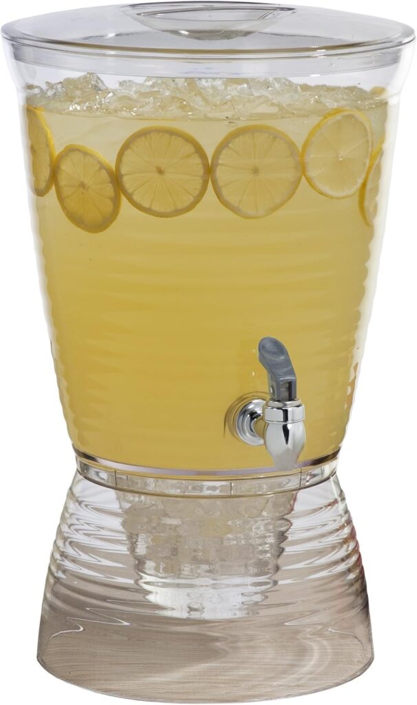 Glass drink dispenser with fruit and ice core at an outdoor table.