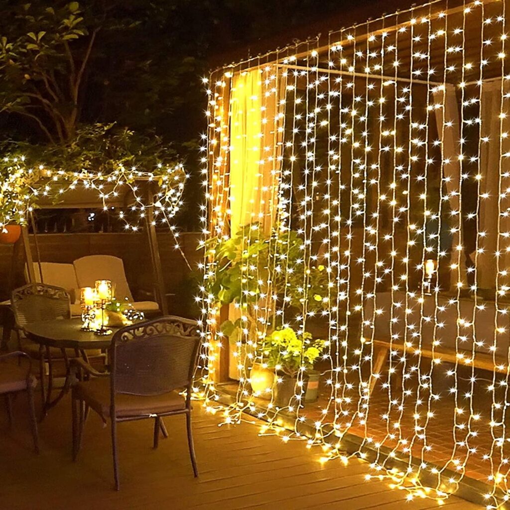 Waterproof curtain string lights glowing along a backyard fence.